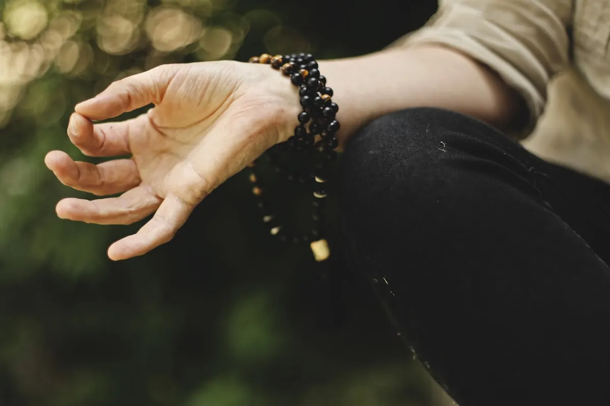 A pair of hands resting in meditation, holding mala beads